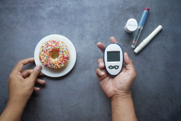 Photo outils de mesure diabétique insuline et beignets sur noir