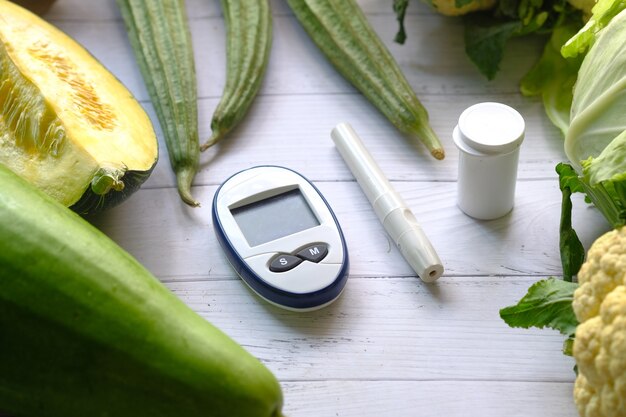 Outils de mesure diabétique et légumes frais sur table.