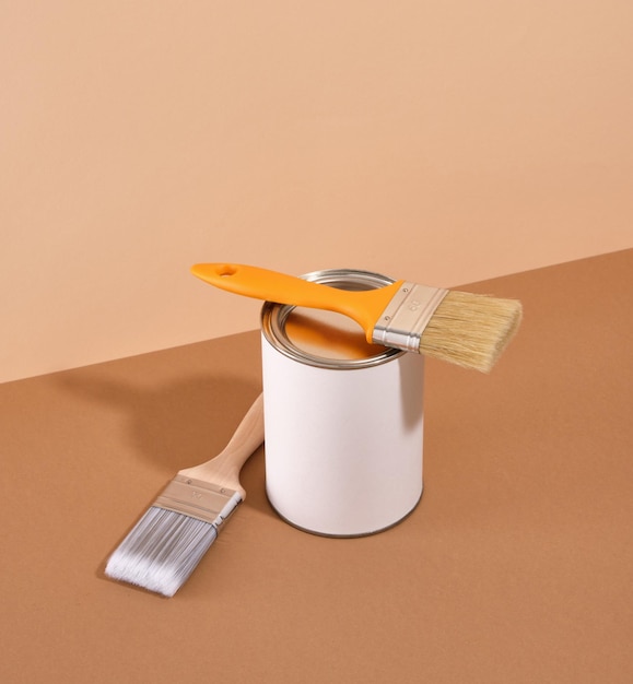 Outils de peinture et boîte en métal blanc avec de la peinture sur fond beige