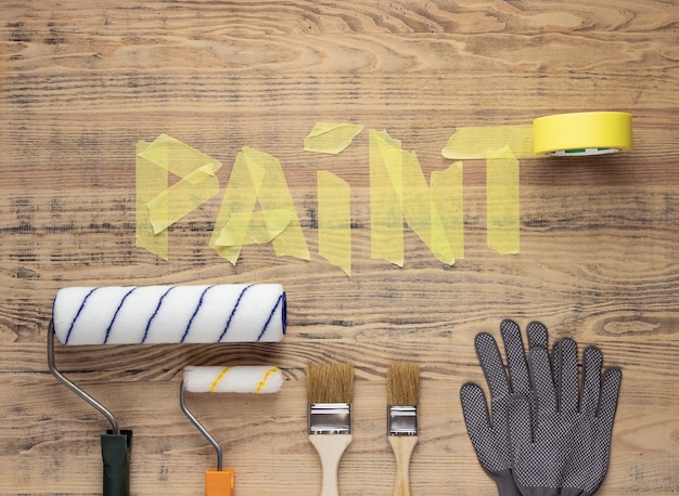 Outils de peinture sur une table en bois avec le mot Peinture à base de ruban adhésif. Rénovation maison ou appartement.