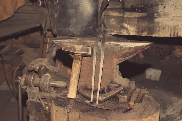 Outils pour marteau en métal sur l'enclume dans la forge