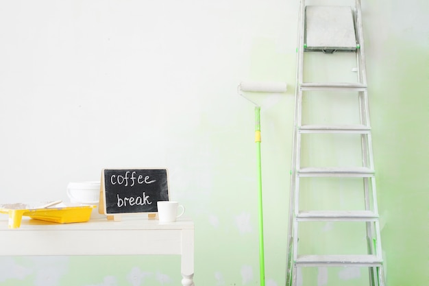 Des outils pour peindre les murs et une tasse de café.