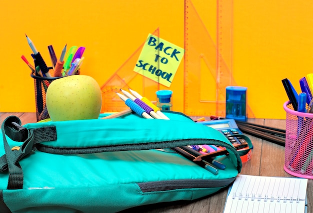 outils scolaires sur un fond orange et l&#39;inscription