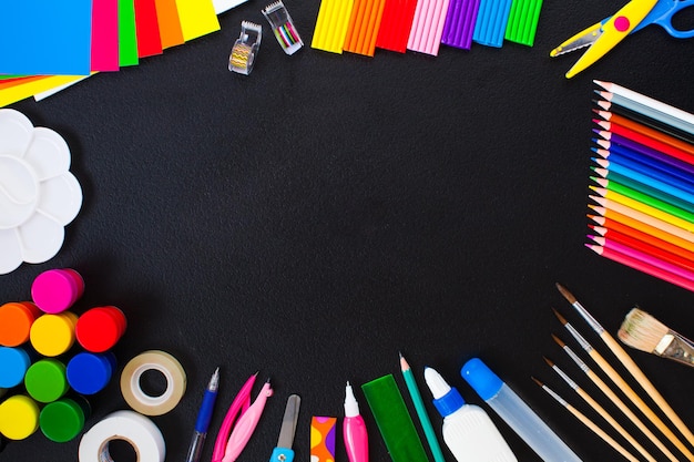 Outils scolaires et de peinture pour la créativité et l'éducation comme bordure sur fond noir. Vue de dessus du lieu de travail créatif. Concept d'art à plat