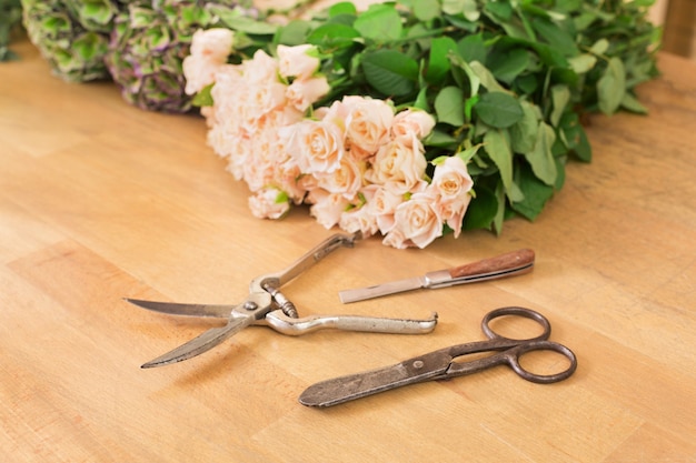 Outils de travail et accessoires de fleuriste, coupe de roses fraîches pour bouquet dans un magasin de fleurs. Livraison de fleurs, création de commande