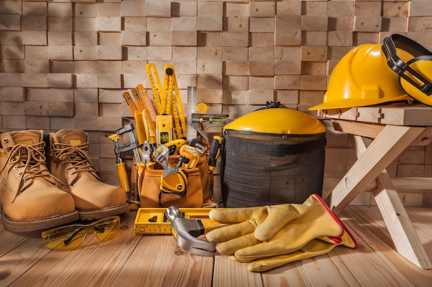 Photo outils de travail de charpentier jaune sur le chantier de construction. sur fond de pile de poutres en bois.
