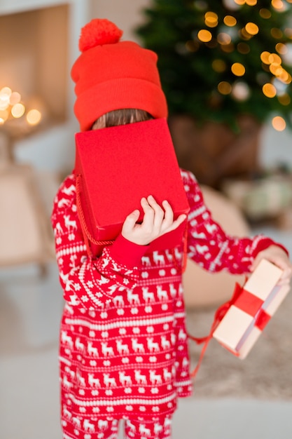 L'ouverture De L'enfant Est Présente Au Sapin De Noël à La Maison Garçon En Pyjama Rouge