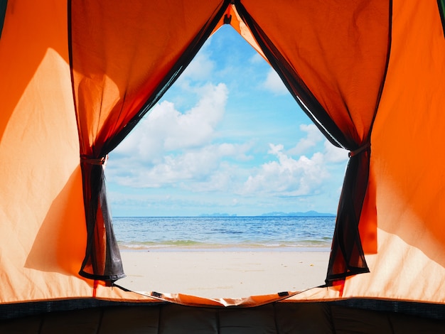 Ouverture de la tente orange camping sur la plage d'été