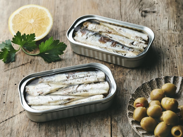 Ouvrez les boîtes et les olives de sardines sur la table en bois rustique