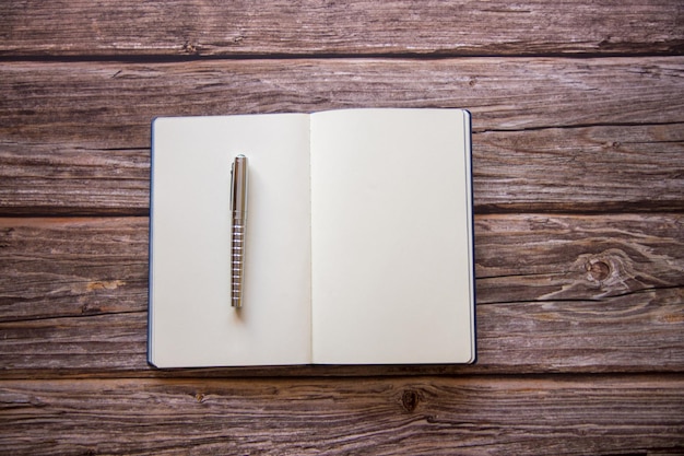 Ouvrez un cahier blanc vierge avec un stylo sur un bureau en bois