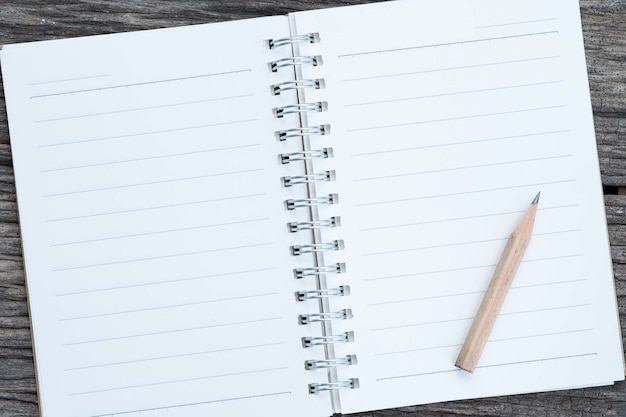 Ouvrez le cahier vierge et un crayon sur fond de bois.