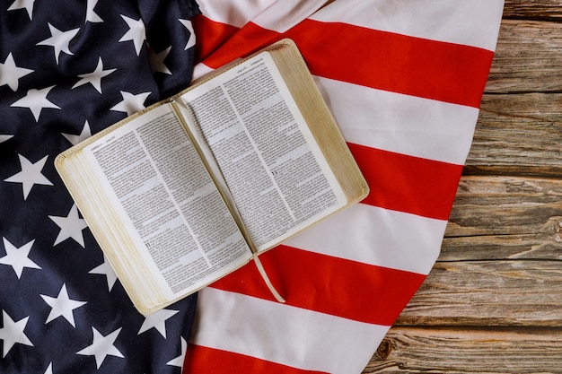 Ouvrez est en train de lire le livre de la Sainte Bible avec la prière pour l'Amérique sur le drapeau américain à volants dans la table en bois