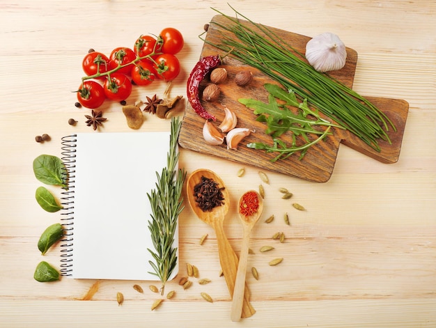 Ouvrez le livre de recettes avec des herbes fraîches tomates et épices sur fond de bois