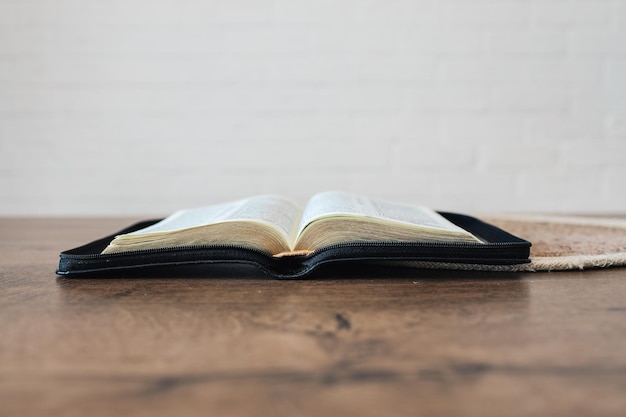 Ouvrez la Sainte Bible sur une vieille table en bois et fond de mur blanc Concept de religion