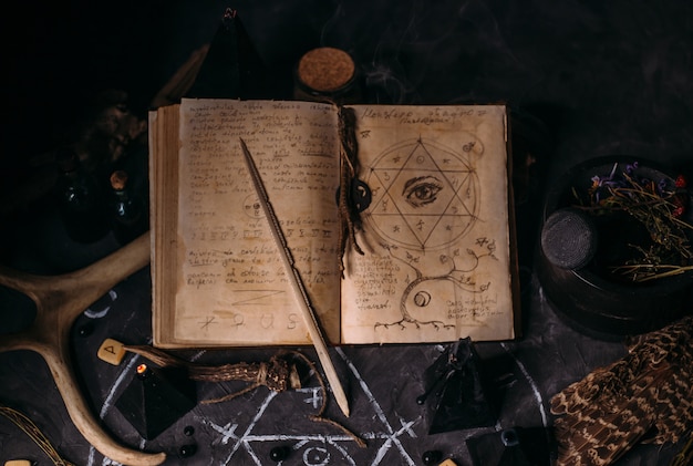 Ouvrez le vieux livre avec des sorts magiques, des runes, des bougies noires sur la table des sorcières. Concept occulte, ésotérique, divination et wicca. Scène d'Halloween