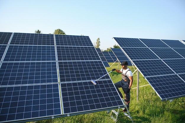 ouvrier afro-américain nettoyant un panneau solaire dans une centrale solaire