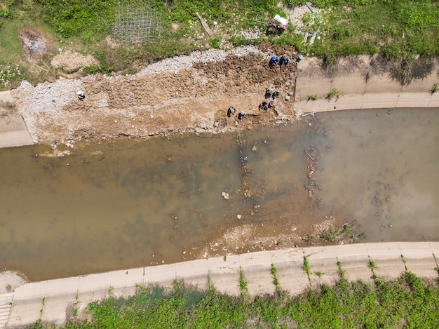 Ouvrier asiatique construisant un canal public en béton