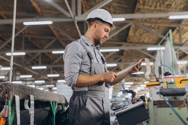 Un ouvrier barbu d'usine programme une fraiseuse CNC avec espace de copie