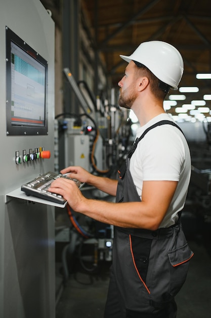 Un ouvrier barbu d'usine programme une fraiseuse CNC avec espace de copie