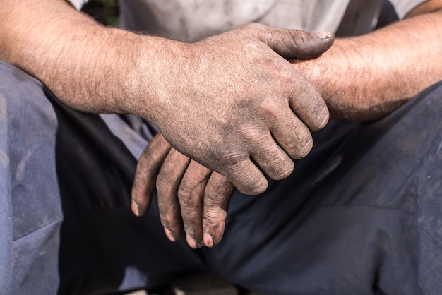 Ouvrier brûleur de charbon de bois avec les mains sales. Ouvrier, mains