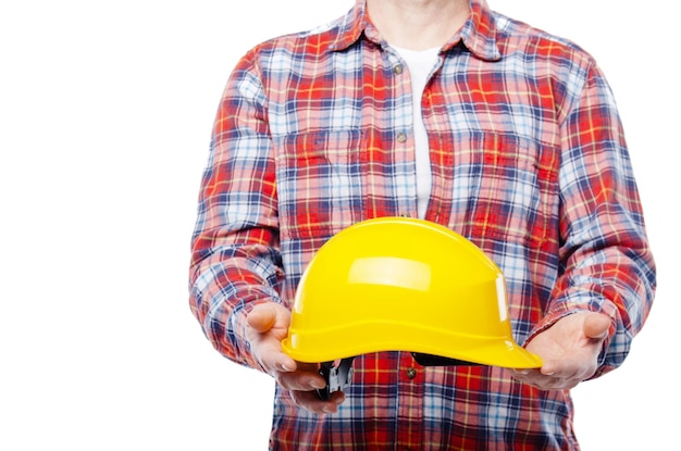 Ouvrier caucasien d'âge moyen tient un casque jaune dans ses mains sur fond blanc
