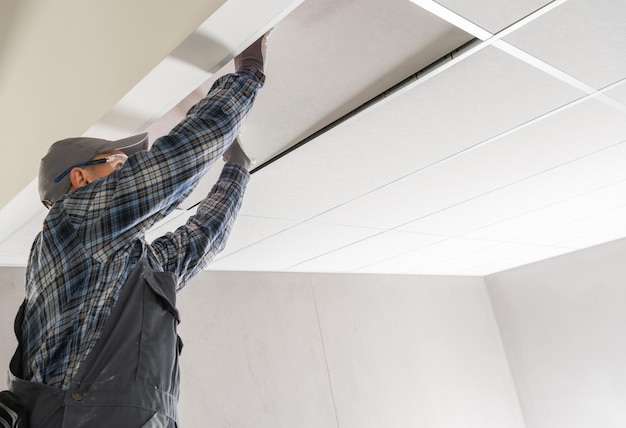 Photo un ouvrier de chantier installe un plafond suspendu