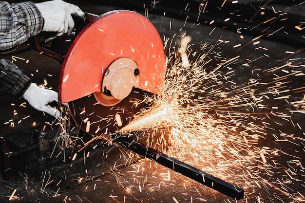 Photo un ouvrier coupe du métal avec une scie circulaire dans une usine.