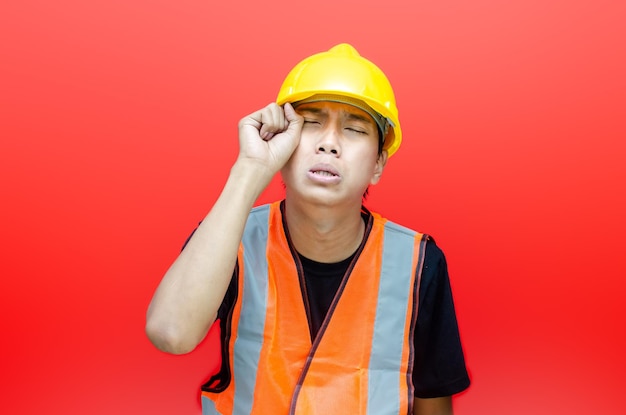 ouvrier du bâtiment asiatique utilisant un casque jaune et un gilet orange avec des pleurs.geste