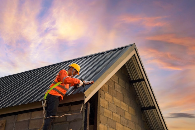 Ouvrier du bâtiment couvreur installer un nouveau toit, outils de toiture, perceuse électrique utilisée sur de nouveaux toits avec feuille de métal.