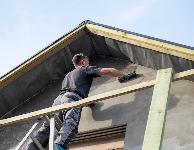 Ouvrier du bâtiment plâtrant la façade de la maison. Application d'enduit de façade