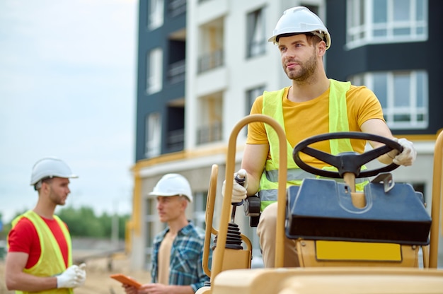 Ouvrier du bâtiment serein et ses deux collègues à l'extérieur