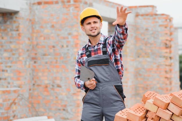 Ouvrier du bâtiment en uniforme et équipement de sécurité a un travail sur le thème industriel de la construction