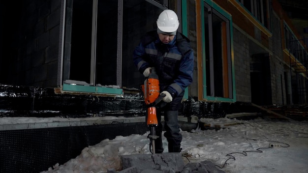 Un ouvrier du bâtiment utilise une perceuse hydraulique sur un chantier de construction pour couper du béton.