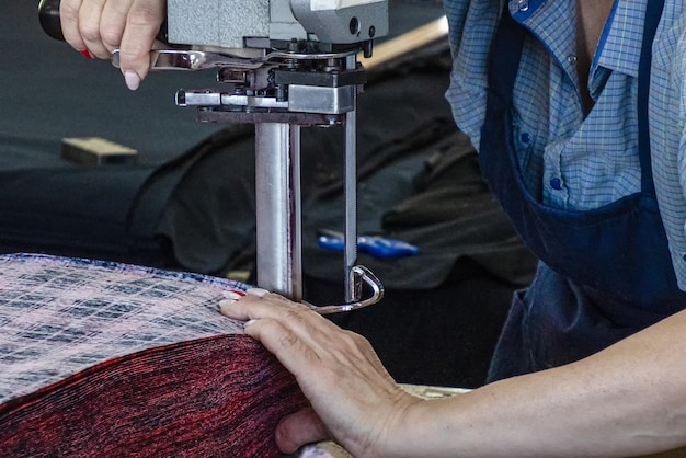 Un ouvrier du vêtement utilise une machine électrique pour couper le tissu Industrie textile Lieu de travail