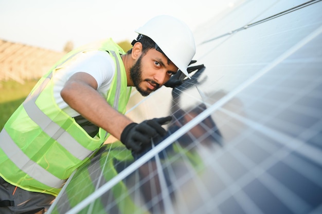 Photo un ouvrier indien en uniforme et avec des outils travaille sur une ferme de panneaux solaires