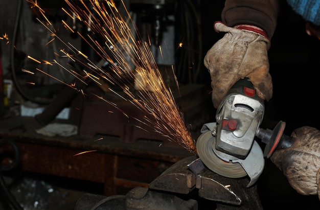 Ouvrier de l'industrie lourde coupant de l'acier avec une meuleuse d'angle