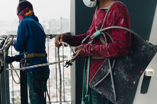 Ouvrier industriel ajustant le matériel d'escalade préparant la corde de sécurité