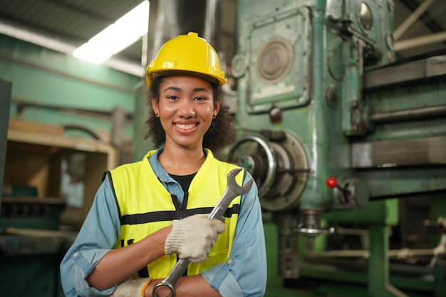 Ouvrier industriel féminin dans le casque avec l'usine de fabrication de l'industrie lourde en arrière-plan avec diverses pièces de projet de métallurgie.Travailler à l'usine de fabrication de l'industrie lourde.