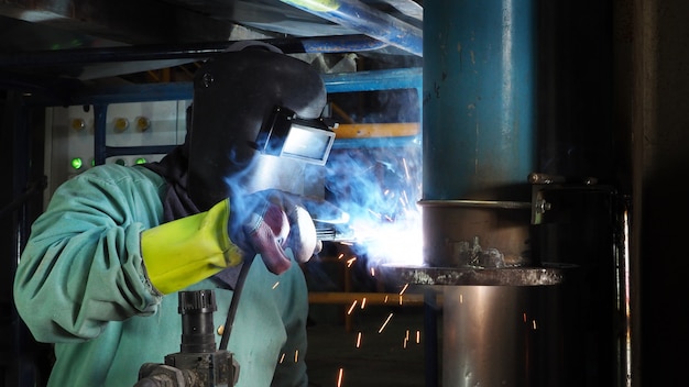 Ouvrier industriel soudure bride de tuyau en acier, une soudure par étincelle.