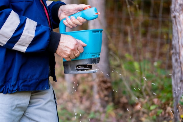 Ouvrier de jardin dans la cour résidentielle avec pelouse fertilisante