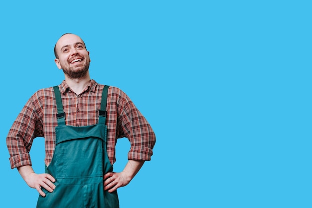 Un ouvrier joyeux sourit en studio tourné avec les bras sur les hanches ce jeune professionnel respire la positivité