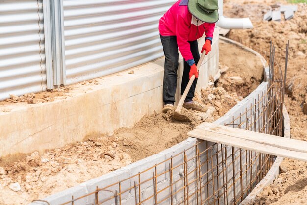 Un ouvrier nivelant le sol avec une pelle sur un chantier de construction