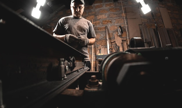 Un ouvrier prépare une machine à bois pour le travail dans son atelier à domicile Fabrication de produits métalliques de vos propres mains