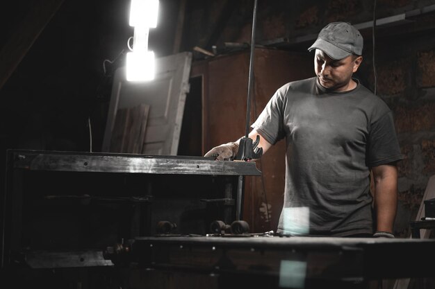 Un ouvrier prépare une machine à bois pour le travail dans son atelier à domicile Fabrication de produits métalliques de vos propres mains