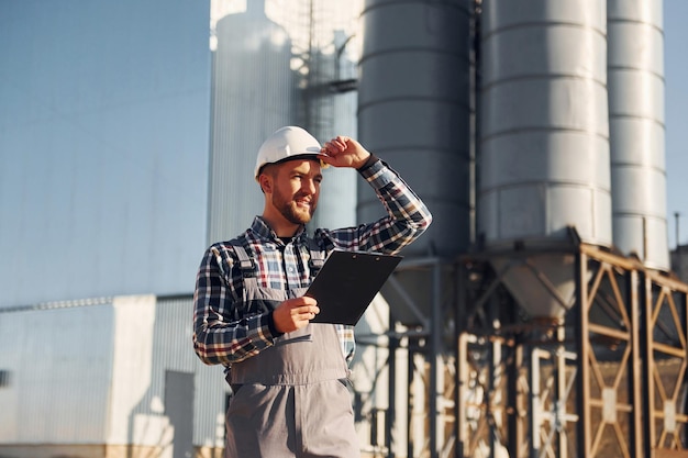 Un ouvrier professionnel est à l'extérieur Un ouvrier du bâtiment en uniforme est à l'extérieur près de l'usine