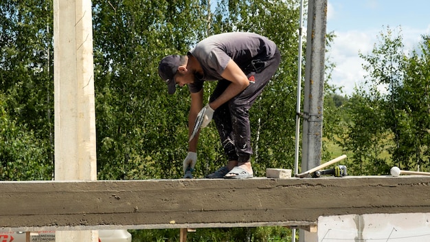 Un ouvrier professionnel pose des blocs de béton Construction d'une maison faite de blocs blancs