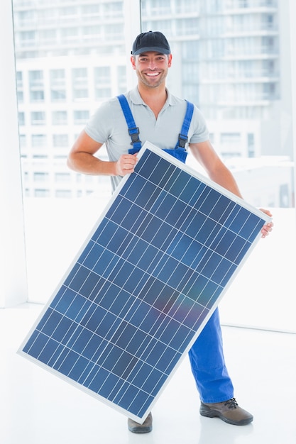 Ouvrier tenant un panneau solaire dans un bureau lumineux