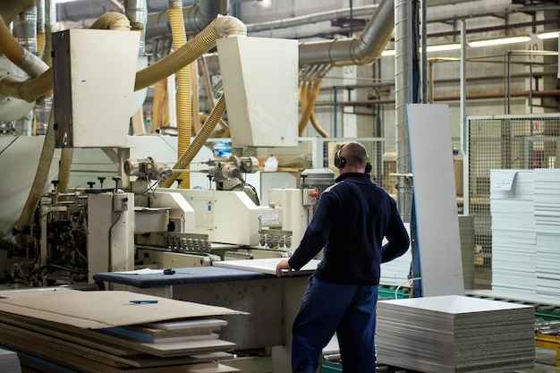 Photo un ouvrier traite des ébauches de meubles sur une machine-outil dans une usine. fabrication industrielle de meubles.