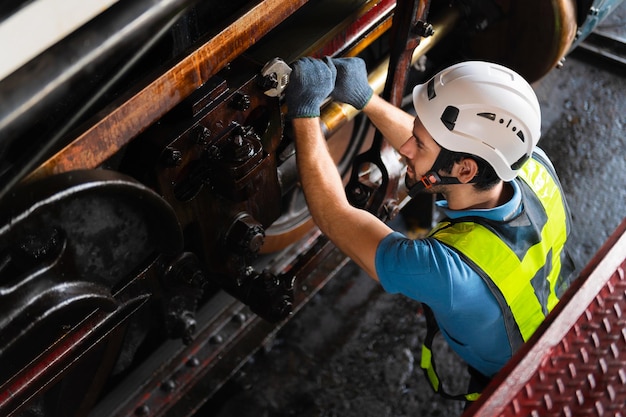 Un ouvrier travaillant dans une usine industrielle utilise un tournevis cruciforme pour inspecter la machine