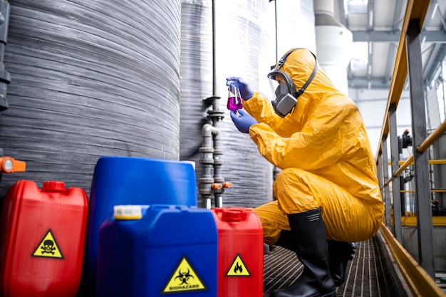 Ouvrier d'usine chimique portant une combinaison de protection et un masque à gaz testant la qualité des produits chimiques